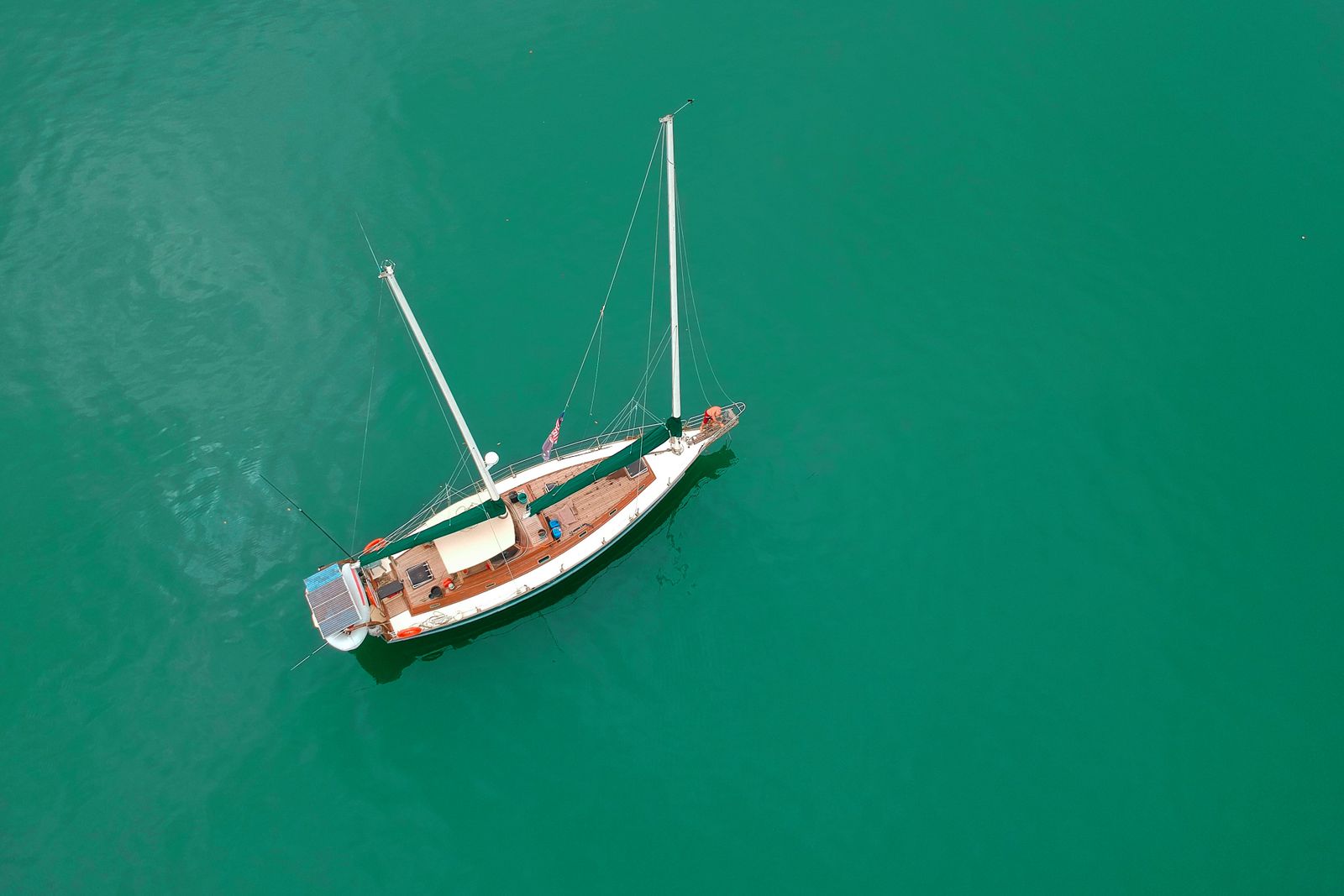Aerial view of a single sailboat anchored on turquoise water
