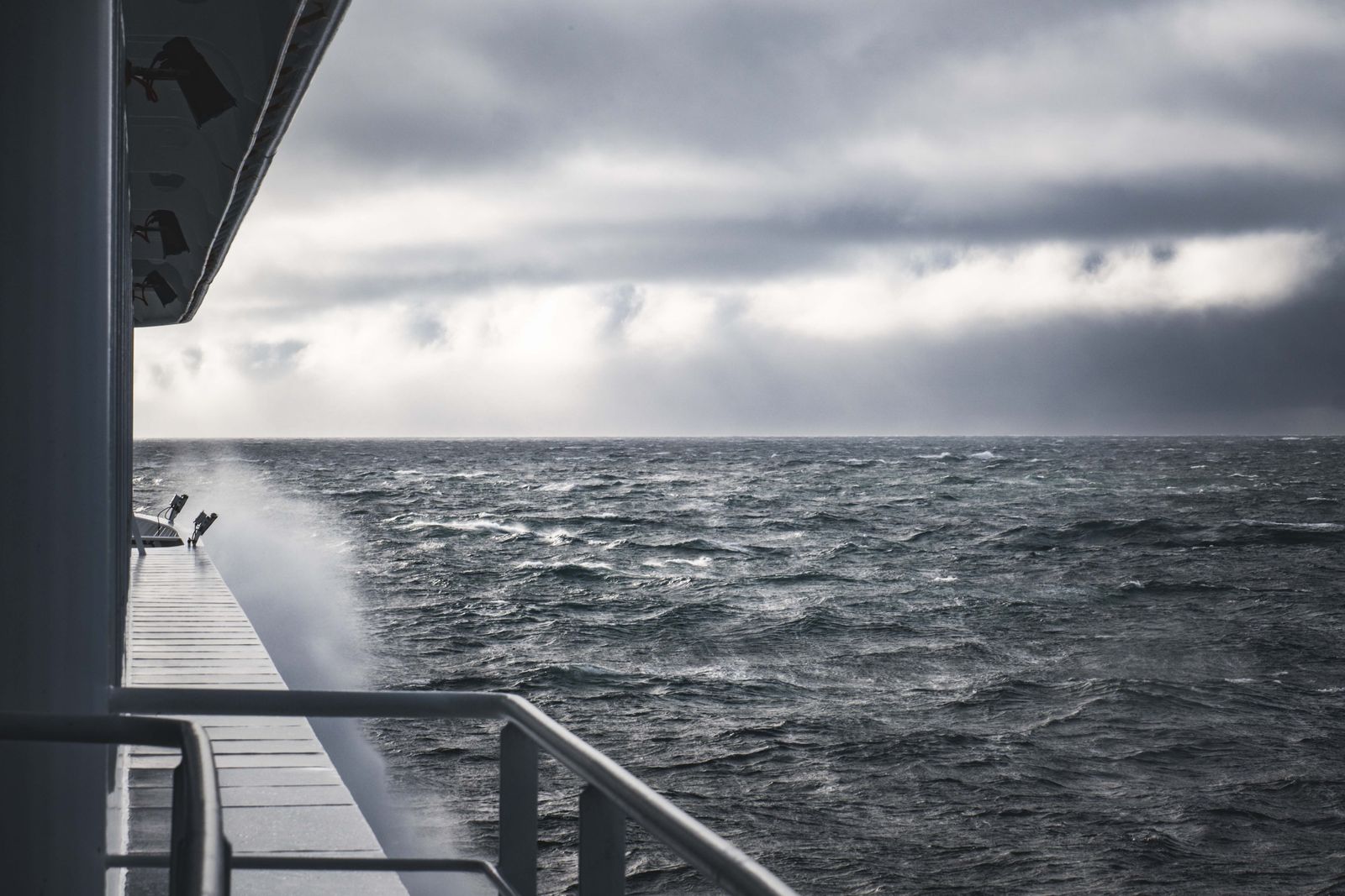 Choppy grey sea under dark clouds seen from a ship deck