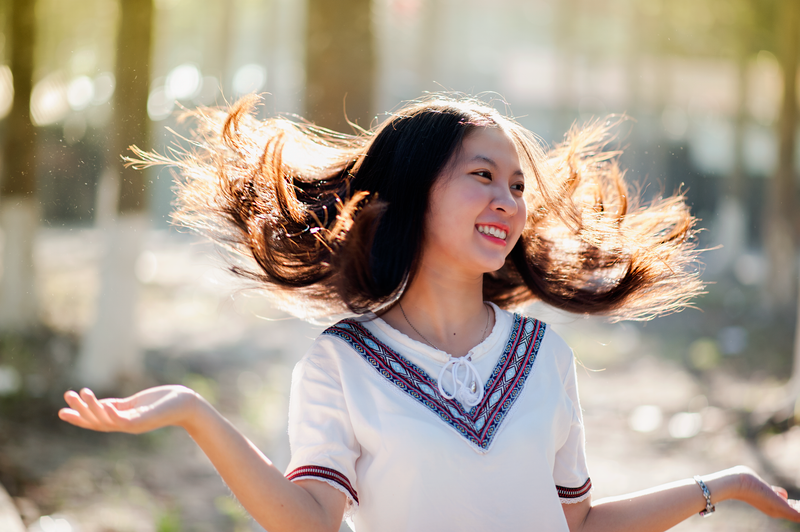 Cheerful young woman with flowing hair smiling in a sunny park