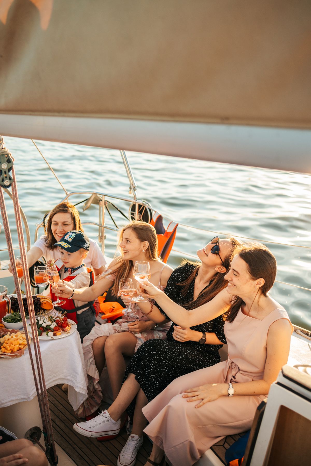 Group of friends celebrating with drinks and food on a yacht at sunset