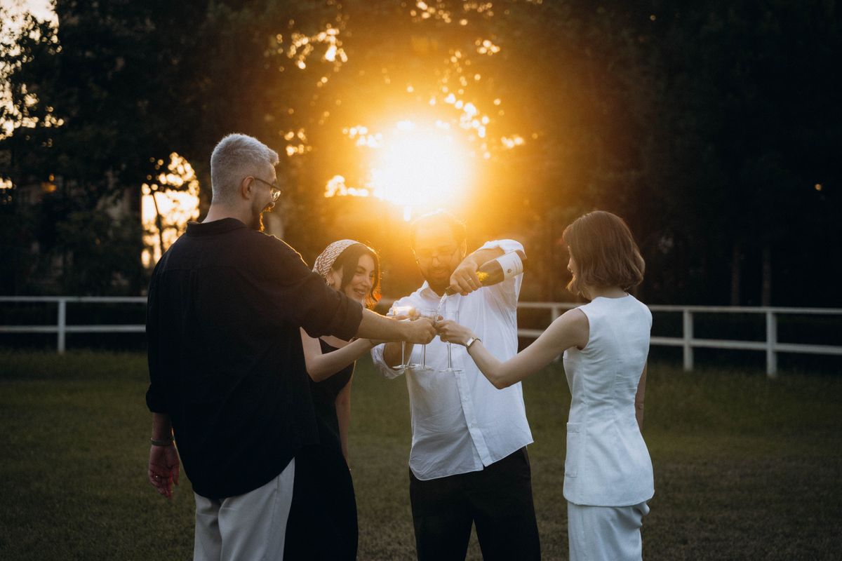 Friends raising a toast with wine glasses outdoors at sunset
