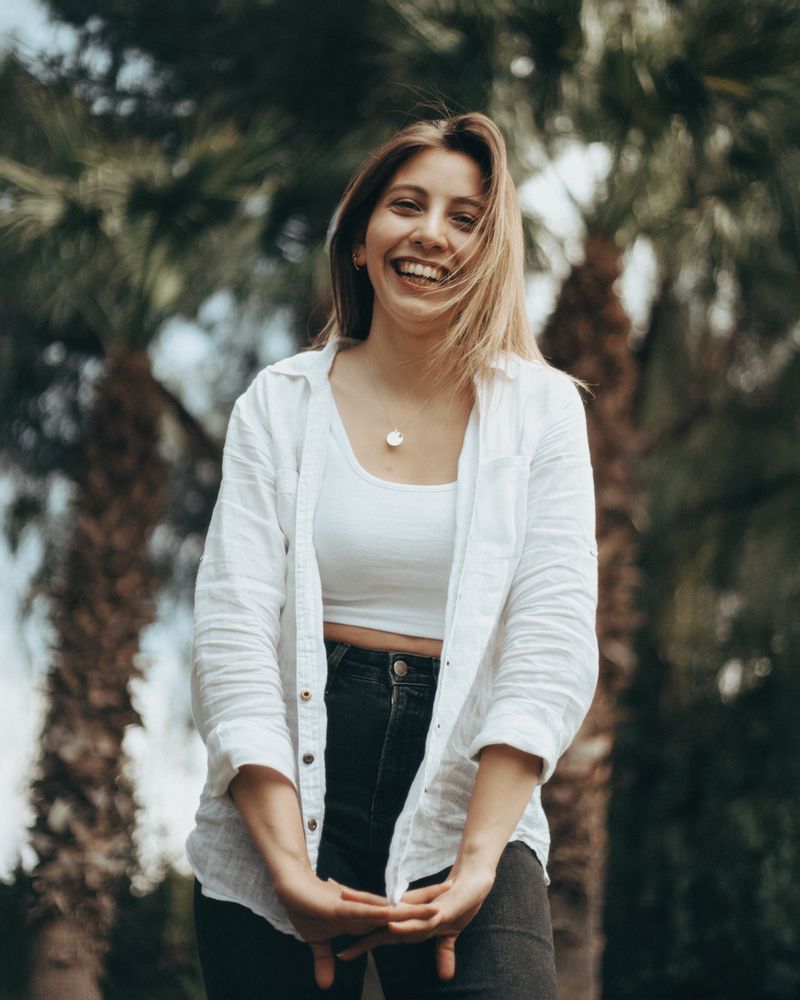 Smiling woman outdoors with palm trees on a sunny day